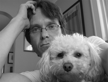 Author Harry Bliss poses for the camera with his small white dog in a grey-scale picture